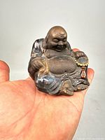 Front view of the antique Chinese Buddha figurine showing the seated Buddha smiling and holding a beaded bracelet.