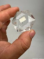 Close-up of a hexagonal faceted polished clear quartz stone held in hand showing geometric facets and transparent appearance.