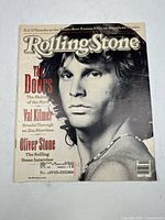 Front cover of Rolling Stone magazine featuring a black and white close-up photo of Jim Morrison from The Doors, with cover text about The Doors, Val Kilmer, Oliver Stone.
