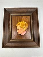 Frontal image of the framed vintage painting depicting a cartoon style child profile with blonde hair and pink collar.