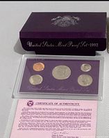 Outer purple box, plastic lens with coins, certificate of authenticity