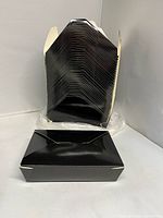 Stack of folded black paper boxes with one assembled example