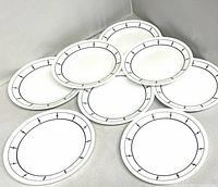 Eight white Corelle plates with black accent border, front view