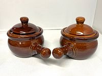 Front view of both brown stoneware crocks with lids attached