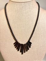 Necklace on display form showing bead strand and fan bar drop