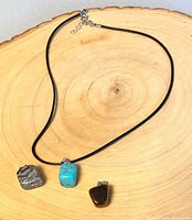 Necklace cord and three stone pendants displayed on wooden surface