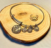 Bangle with four charms and open band ring displayed on wood base