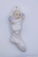 Front view of porcelain stocking ornament showing baby figure and inscription