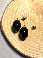 front view of onyx drop earrings on wood slice