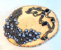 Both necklaces displayed on wood slice, showing overall design and contrast between pearl and rhinestone pieces