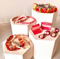 Group shot of five bracelets and two pairs of earrings displayed on pedestals