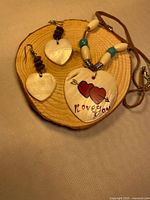 Necklace pendant and both earrings on wooden disc