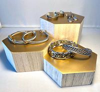 Group shot of all three bracelets and both earring pairs displayed on gold blocks