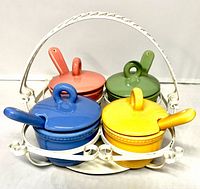 Front view of full set showing four coloured bowls with lids and spoons in white carrier