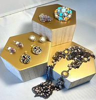 Group view of all jewelry items on gold stands with necklace, earrings, brooches and bag