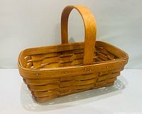 Angled side view of rectangular Longaberger basket showing weave, rim rivets, fixed handle