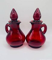 Front view of both ruby red cruets with stoppers inserted