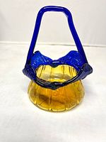 Front view of amber glass basket with cobalt blue rim and handle