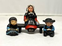 Front view of three figurines and bench