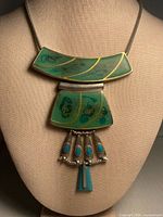 Front view of necklace on bust showing enamel panels, cabochon drops and chain