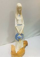 Front view of porcelain figurine showing girl with blue hat