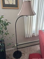 Full view of floor lamp showing base, curved metal stand, and lampshade.