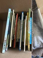 Side view of vintage children's books in a box showing spines and varying thicknesses