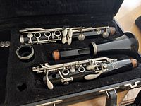 Vito Reso-Tone 3 clarinet disassembled in case showing the three main body sections and mouthpiece; corks on joints show wear, keys are silver-colored metal, black body appears used.
