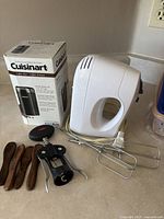 Photo showing boxed Cuisinart coffee grinder, white handheld mixer with beaters, four wooden utensils, and black OXO coffee grinder
