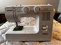 Front view of white Janome 234 electric sewing machine showing stitch selector dial, stitch length dial, stitch pattern guide, and sliding switch.