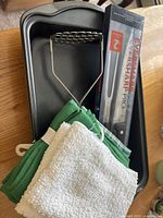 Photo showing black non-stick baking sheets, Eversharp Pro cutlery in box, green kitchen towels and white dish towel.