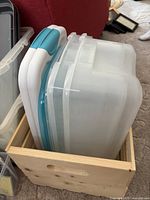 Side view showing three translucent plastic storage bins with lids and a wooden crate base.