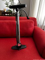Full view of Schwinn bicycle floor pump resting on red sofa showing overall condition and attached hose.