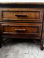 Close-up photo showing the front of one nightstand drawer with faux bamboo style frame and handles in medium brown wood finish.