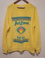 Front view of yellow Arizona Iced Tea sweater featuring colorful geometric design and text.