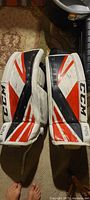 Pair of CCM 28+1 goalie pads front view showing red, white, and black color scheme and CCM branding.