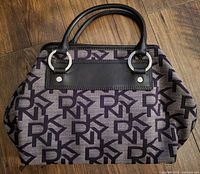 Front view of the DKNY medium satchel bag showing the monogram canvas and leather handles with silver rings.