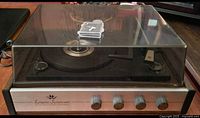 Side view of Longines Symphonette turntable with closed dust cover, showing front panel with three control knobs.