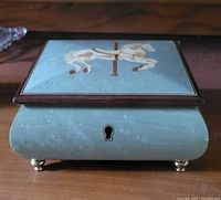 Top view of the closed music box showing the carousel horse decoration on the lid.