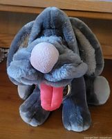 Front view of the gray plush dog showing face, large nose, red tongue, and The Heritage Collection tag.