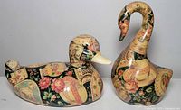 Ceramic swan and duck figures decorated with floral fabric applique, shown side by side from an angle