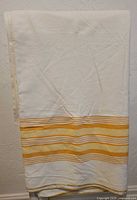 Full view of the folded vintage cream flannelette sheet with yellow and tan wide stripes near the edge.