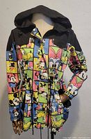 Front view of lightweight jacket showing colorful Disney character block print, black shoulders, and hood. Drawstring waist visible.