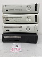 Front view of four stacked Xbox 360 consoles showing cosmetic condition
