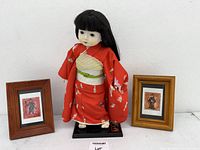 Japanese doll flanked by two framed paintings
