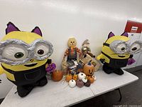 Tabletop view of entire lot including both inflatable Minions, scarecrows, pumpkins, hay bale and string lights