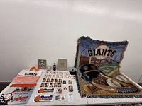 Wide shot of entire lot on table showing blanket, caps, cards, tote, towel, stickers, bottle