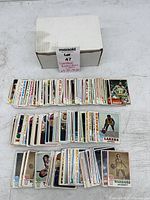 Overall view of two stacked rows of vintage NBA cards beside white storage box