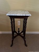 Full frontal photo of antique Victorian side table showing marble top and carved wood base with turned legs and central finial.