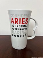 Front view of the white ceramic Aries zodiac mug showing text descriptions of characteristics.